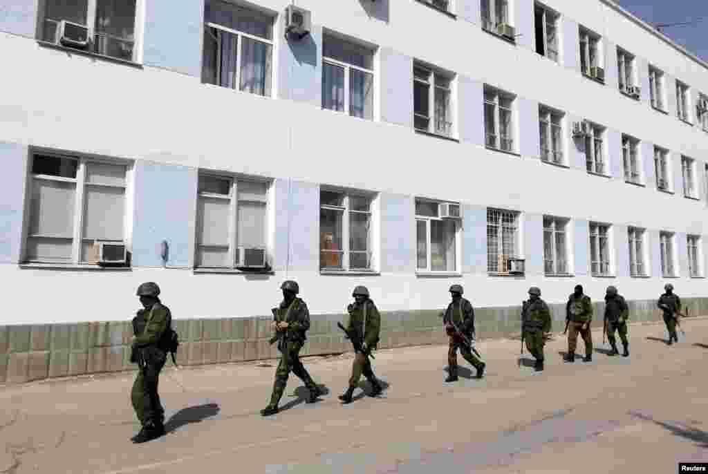 Pria bersenjata, diyakini sebagai tentara Rusia, berjalan di wilayah markas besar angkatan laut di Sevastopol, Krimea, 19 Maret 2014.