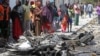 Somalis stand over the wreckage of car bomb which exploded outside a restaurant in Mogadishu, Somalia, April , 21, 2015.