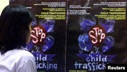 FILE - A Filipino girl looks at posters condemning child trafficking inside a shelter for runaway child laborers in Manila.