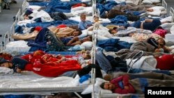 Para migran beristirahat di sebuah kamp penampungan sementara di stadion olahraga kota Hanau, Jerman hari Selasa (22/9).
