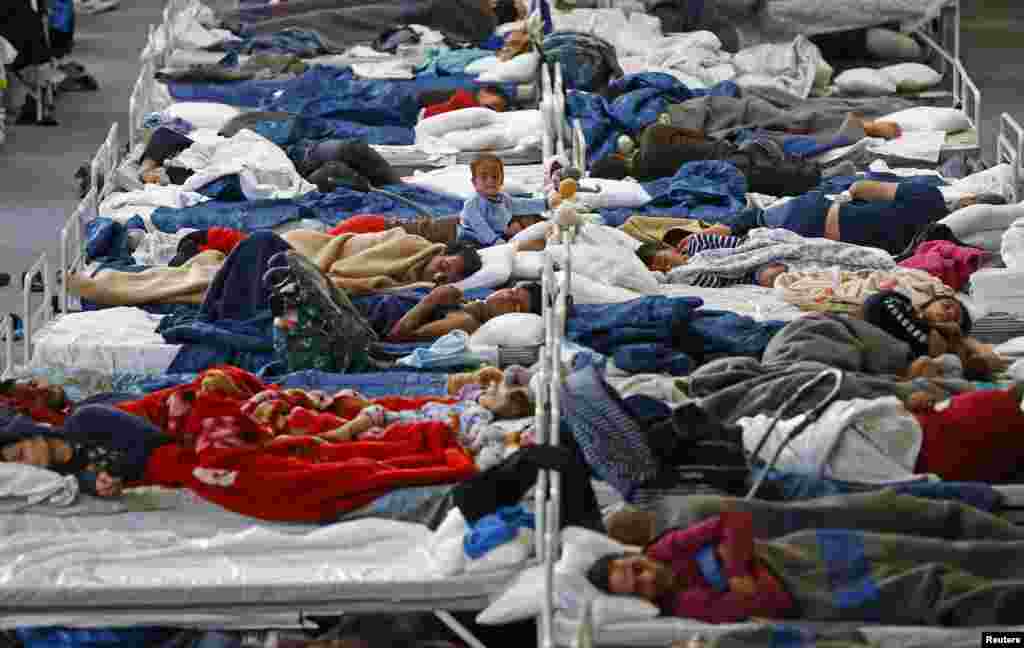 Migrants rest on beds at an improvised temporary shelter in a sports hall in Hanau.