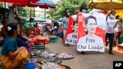 Pengunjuk rasa anti-kudeta berunjuk rasa dengan membawa gambar pemimpin Myanmar yang digulingkan Aung San Suu Kyi, melewati pasar Kotapraja Kamayut Yangon, Myanmar, Kamis, 8 April 2021. (Foto: AP)