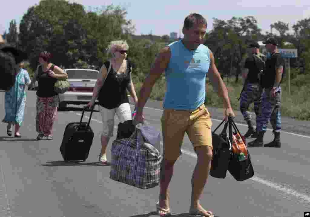 Self-proclaimed Donetsk People&#39;s Republic policemen watch people fleeing Shakhtarsk, Donetsk region, eastern Ukraine, July 28, 2014.