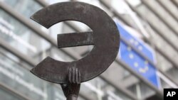 A statue shows the Euro symbol flipped, at the European Commission headquarters in Brussels, Belgium, March 7, 2012. 