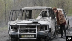 Cư dân địa phương xem xét một chiếc ô-tô bị đốt cháy sau vụ đụng độ tại làng Bulbasika gần Slovyansk, chủ nhật 20/4/2014.