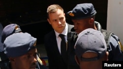 FILE - South African Olympic and Paralympic sprinter Oscar Pistorius is escorted to a police van after his sentencing at the North Gauteng High Court in Pretoria, Oct. 21, 2014.