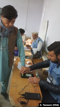 A man in a Kabul polling station is getting his fingerprints taken on the new biometrics system introduced to reduce fraud in elections, Oct. 20, 2018.