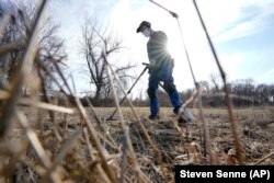 Amateur historian Jim Bailey uses a metal detector to look for Colonial-era items in a field, March 11, 2021, in Warwick, R.I. (AP PHOTO/Steven Senne)