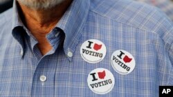 FILE - A man wears stickers after casting his ballot at the Hamilton County Board of Elections in Cincinnati, Oct. 10, 2018. In addition to choosing candidates, voters are deciding ballot initiatives.