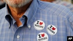 Un hombre luce calcomanías en su camisa después de votar en la Junta de Elecciones del Condado de Hamilton en Cincinnati, el 10 de octubre de 2018. Además de elegir candidatos, los votantes están decidiendo varias iniciativas en la votación.