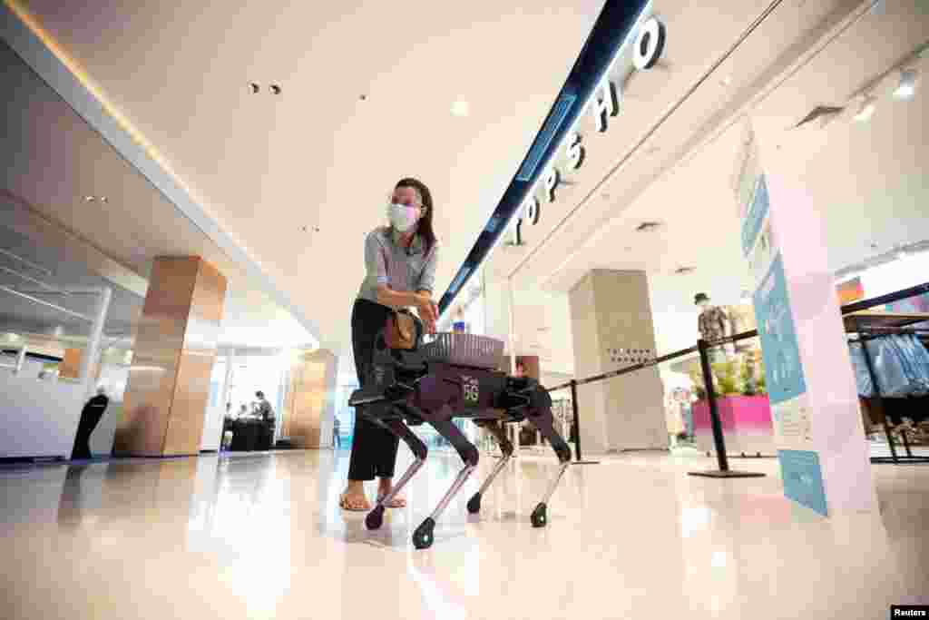 A woman uses hand sanitizer gel from a four-legged dog robot called &quot;K9&quot; at the Central World department store, after the Thai government eased isolation measures to prevent the spread of the COVID-19 in Bangkok, Thailand.