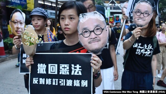 2019年4月28日香港大游行的示威者手持在监狱服刑的邵家臻及戴耀廷的头像，代替他们出来游行 (美国之音汤惠芸 拍摄）