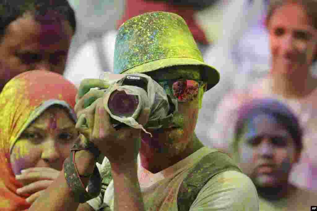 Một người chụp hình che chắn máy của mình khỏi bị dính sơn màu trong Lễ hội Màu sắc do Trung tâm Văn hóa Ấn Độ tổ chức tại Cairo, Ai Cập.