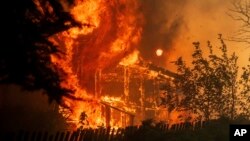 Flames consume a home as the River Fire tears though Lakeport, Calif., July 31, 2018. 