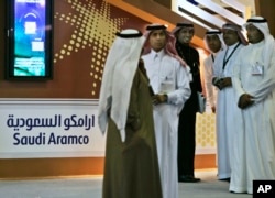 FILE - Employees of the Saudi Aramco oil company prepare for the first day of the Arab Oil and Gas exhibition in Dubai, United Arab Emirates.