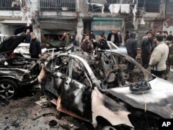 In this photo released by the Syrian official news agency SANA, Syrian citizens and security forces gather next to damaged cars at the scene where an explosion hit a commercial street, in the costal town of Jableh, Syria, Jan. 5, 2017. The blast, which left several killed or injured, undermined a nearly week-old Russia- and Turkey-brokered cease-fire.