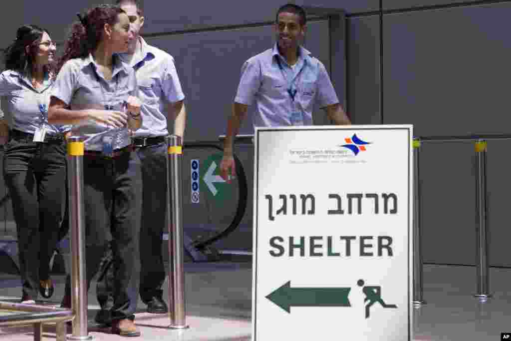 Israeli airport workers pass a sign pointing to a shelter for refuge in case a warning siren indicates the possibility of an incoming rocket, at Ben Gurion International airport, Tel Aviv, July 23, 2014.
