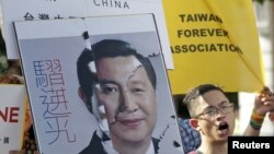 Một nhà hoạt động cầm tấm bảng ghép hình chân dung Tổng thống Đài Loan Mã Anh Cửu và Chủ tịch Trung Quốc Tập Cận Bình, biểu tình chống lại cuộc gặp sắp tới ở Singapore giữa ông Mã và ông Tập, ở trước văn phòng Tổng thống ở Đài Bắc, Đài Loan, ngày 6/11/2015.
