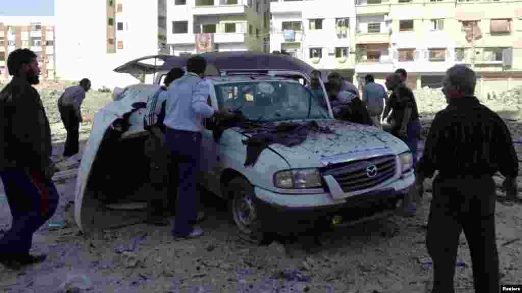 Men search for casualties inside a damaged car after what activists say was an air strike by forces loyal to Syrian President Bashar al-Assad, Hammouriyeh, Syria.