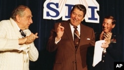 FILE - U.S. President Ronald Reagan is flanked by physicist Dr. Edward Teller, left, and Lt. Gen. James A. Abrahamson, director of Strategic Defense Initiative, as he arrives to address a conference marking the first five years of his "Star Wars" missile defense program in Washington, D.C., March 14, 1988. 