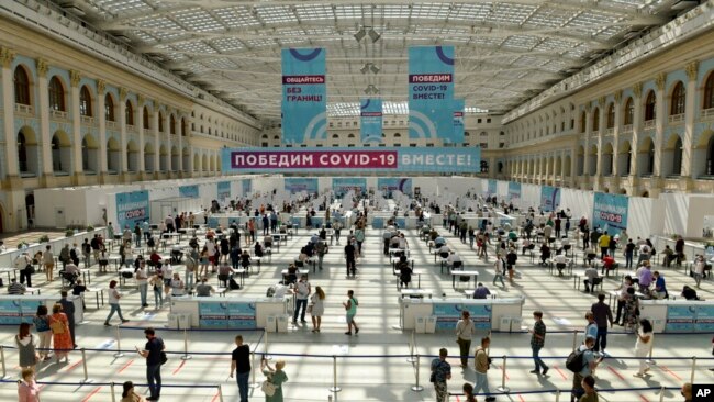 People wait in line for a COVID-19 vaccine at a vaccination center in Gostinny Dvora, a huge exhibition place in Moscow, Russia, as the country faces a sharp surge in coronavirus cases.