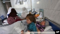 Farida, 7, and her mother lay on the bed at hospital after a militant attack on a Shiite shrine in Kabul, Afghanistan, Wednesday, Oct. 12, 2016. More than a dozen people were killed in the attack on a Shiite shrine in Kabul, an official said. (AP Photo/Rahmat Gul)