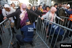 Residents of the Brussels suburb of Molenbeek are searched by police vefore taking part in a memorial gathering to honor the victims of the recent deadly Paris attacks, in Brussels, Belgium, Nov. 18, 2015.