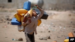 FILE - A boy carries buckets to fill with water from a public tap amid an acute shortage of water Oct. 13, 2015, on the outskirts of Sanaa, Yemen.