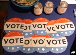 FILE - Computer mouse pads with Secure the Vote logo on them are seen on a vendor's table at a convention of state secretaries of state in Philadelphia, July 14, 2018.