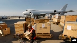 FILE - A worker carries a box with U.N. equipment at the Damascus airport in Syria, May, 8, 2012. 