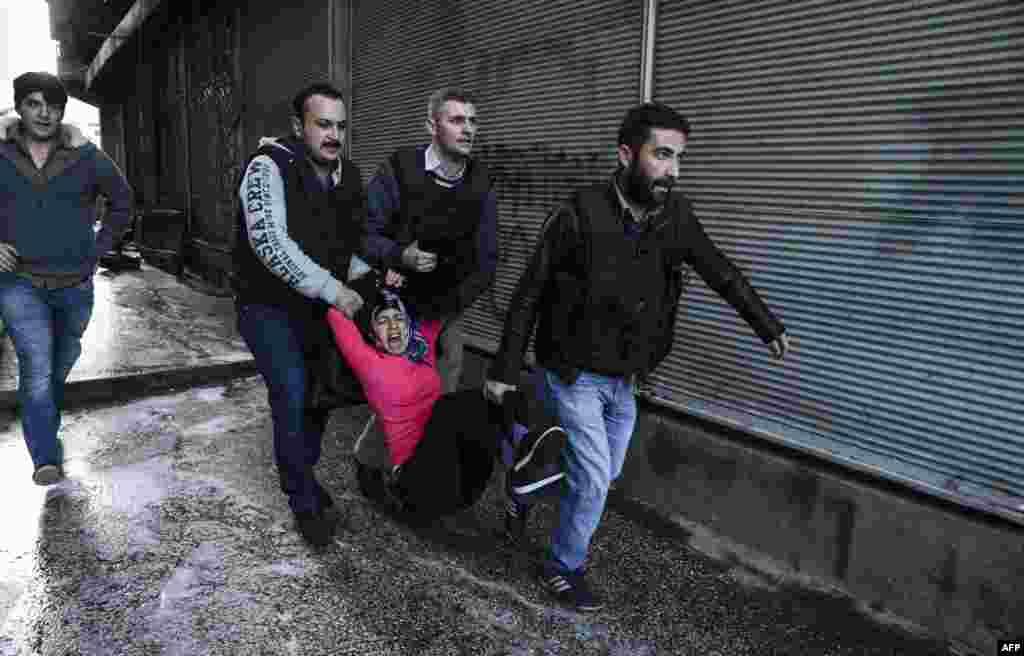 Turkish plain clothes police officers detain a woman during a protest against the curfew in the Sur district of Diyarbakir.