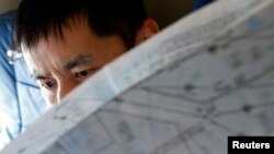 FILE - A Japan Coast Guard officer studies a map onboard their Gulfstream V Jet aircraft, customized for search and rescue operations, as they search for the missing Malaysia Airlines MH370 plane over the waters of the South China Sea, March 15, 2014.