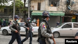 手持武器的缅甸警察在街头巡逻。