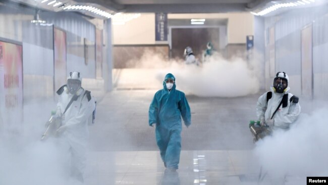 身穿防护服的工作人员在中国湖南长沙市的一个地铁站里喷洒消毒液以防范新冠病毒。（2020年2月4日）