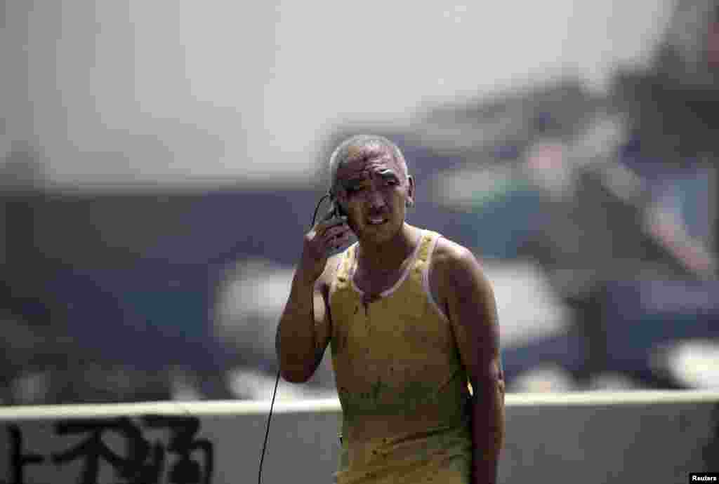 A survivor talks on his mobile phone at the site of the explosions at the Binhai new district in Tianjin. Two huge explosions tore through an industrial area where toxic chemicals and gas were stored in the northeast Chinese port city of Tianjin, killing at least 44 people, including at least a dozen firefighters, and injuring at least 700 people, officials and state media said.