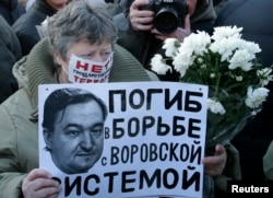 A woman holds a placard with a portrait of Sergei Magnitsky during an unauthorised rally in central Moscow December 15, 2012.
