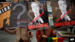 FILE - Activists holds signs depicting Bolivia's former President Gonzalo Sanchez de Lozada during a protest outside the US embassy in La Paz, Bolivia, Sept. 3, 2010.
