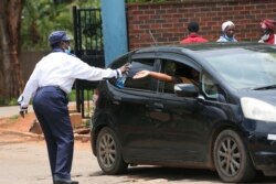 A security guard sanitizes a motorist's hands at the entrance of a health facilty in Harare, Zimbabwe, Nov, 26, 2021.