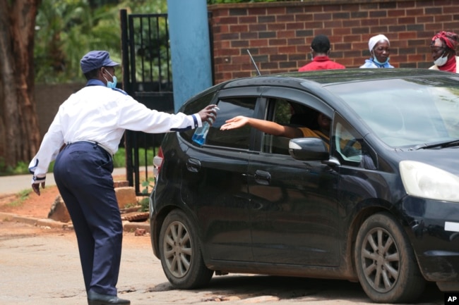 A security guard sanitizes a motorist's hands at the entrance of a health facilty in Harare, Zimbabwe, Nov, 26, 2021.