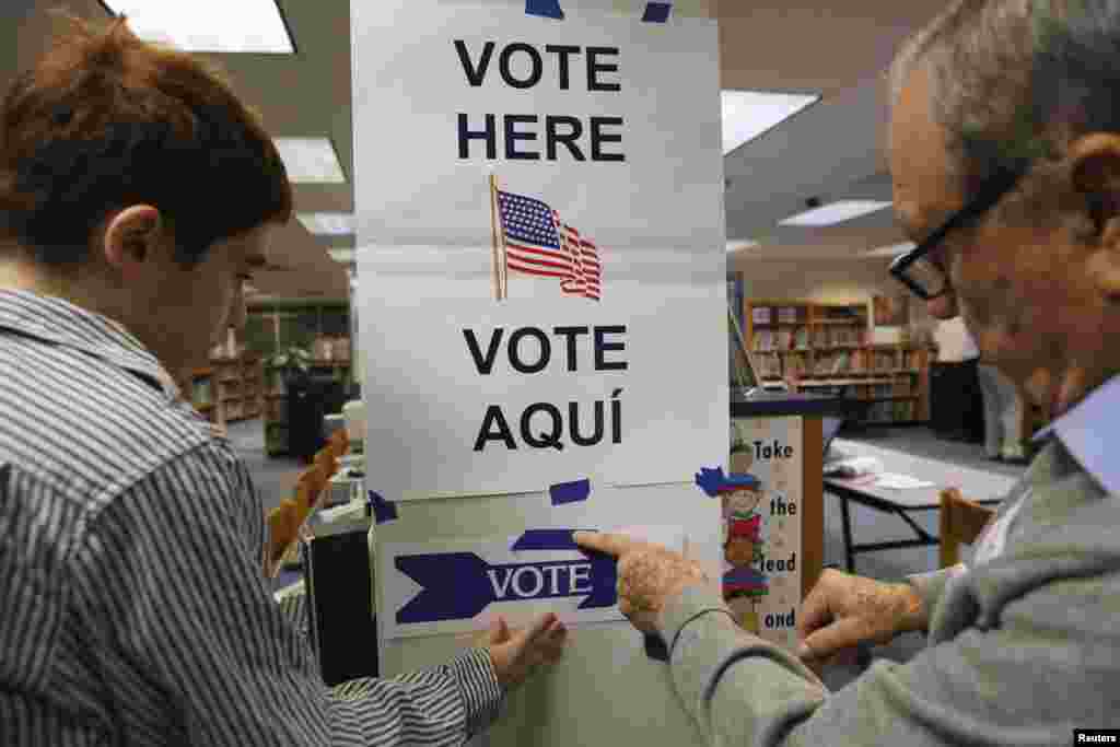 Election workers put up a sign in the library of Spring Hill Elementary School, which is being used as a polling station in McLean, Virginia, Nov. 5, 2013.