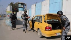 Cảnh sát Iraq kiểm tra chiếc xe hơi tại một trạm kiểm soát trong thủ đô Baghdad, Iraq