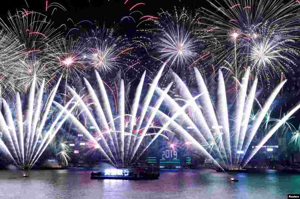 Fireworks explode over Victoria Harbour and Hong Kong Convention and Exhibition Centre during a pyrotechnic show to celebrate the New Year in Hong Kong, China.