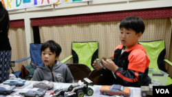 Anderson dan Jamison Cheng berjualan mobil kertas seharga $2 di Pameran Bisnis Anak-anak Gaithersburg (21/7). (Foto: VOA/Andy Masfar)