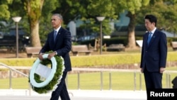 FILE - U.S. President Barack Obama, left, with Japanese Prime Minister Shinzo Abe, prepares to lay a wreath at Japan's Hiroshima Peace Memorial Park, May 27, 2016. Abe will reciprocate by visiting Pearl Harbor, Hawaii, in late December. 