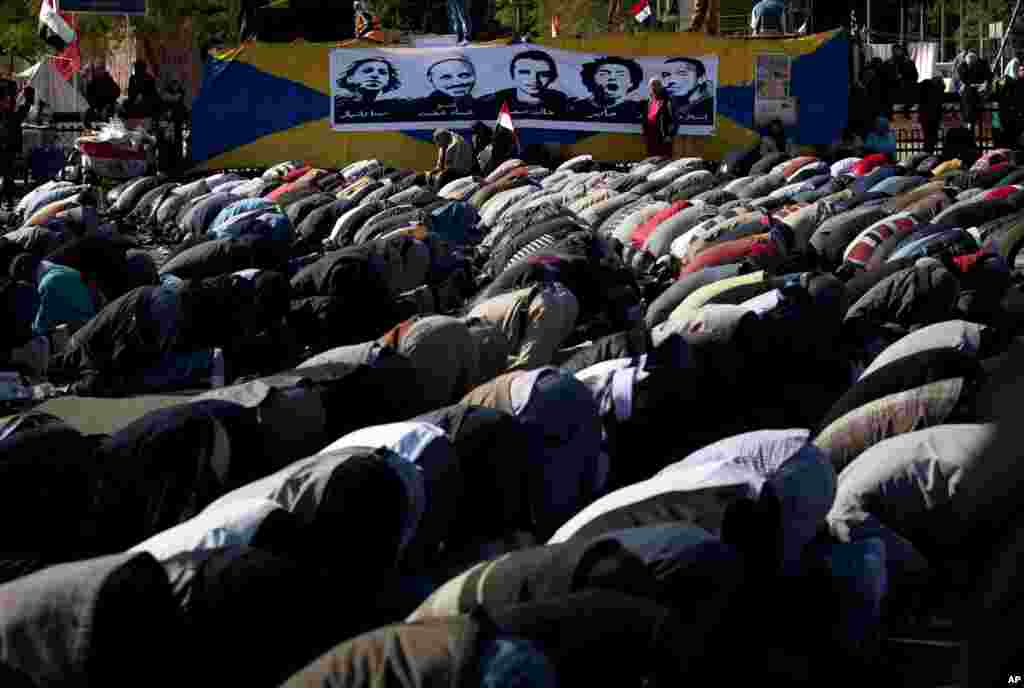 Protesters opposing president Mohamed Morsi attend Friday prayers beneath a poster depicting protesters killed in the Egyptian revolution, Tahrir Square, Cairo, Egypt, December 7, 2012.