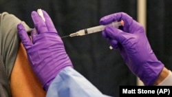 FILE - A man gets a COVID-19 vaccine at a mass vaccination site at the Natick Mall on Wednesday, Feb. 24, 2021, in Natick, Mass. 