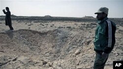Libyan men survey a hole that defected soldiers say was created by an air strike impact the previous week by the Libyan army in the eastern town of Ajdabiya, Libya, on March 1, 2011