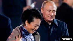 11月10日，正在北京參加APEC會議的俄羅斯總統普京在水立方觀看焰火的時候起身為中國第一夫人彭麗媛披上披肩。