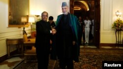 Afghanistan's President Hamid Karzai (R) shakes hands with his Indian counterpart Pranab Mukherjee ahead of their meeting at the Rashtrapati Bhavan presidential palace in New Delhi, May 21, 2013.