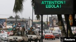 A U.N. convoy of soldiers passes a screen displaying a message on Ebola on a street in Abidjan, Ivory Coast, Aug. 14, 2014. 